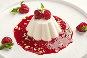 Panna cotta with raspberry syrup, pistachios,berries and mint photo