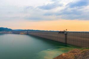 view of the river and mountains on Khun Dan Prakan Chon dam is largest and longest roller compacted concrete dam in the world during sunset in Nakonnarok Thailand. photo