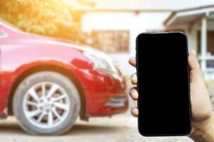 Close-up of female use Hand holding smartphone blurred images touch of Abstract blur of headlight ,window of red car outdoor background. photo