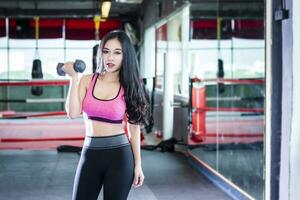 aptitud asiático mujer ejecutando haciendo ejercicios formación con pesa deporte en deporte gimnasio interior y aptitud salud club con Deportes ejercicio equipo gimnasio antecedentes. foto