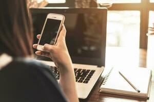 Close-up of business female working with smartphone and laptop in coffee shop like the background. photo