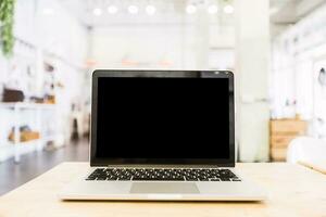 Mockup image of laptop with blank Black screen on wooden table of In the coffee shop. photo