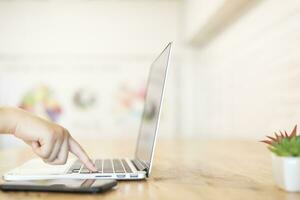 Close-up of business female working hands typing on a laptop keyboard with smartphone in coffee shop like the background photo