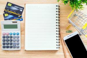 Credit cards,notebook,flower pot tree,smartphone and Shopping cart on wooden background,Online banking Concept,Top view office table. photo