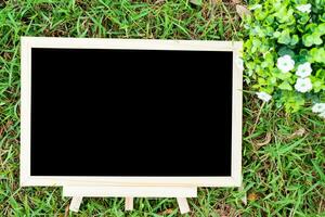 empty wooden blackboard and Flowerpot in square shape on green grass in the park background. photo