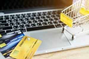 Credit cards and Shopping cart on laptop on wooden background, Online banking Concept,Top view office table. photo