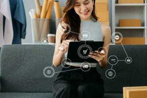 Young woman running online store Startup small business SME, using smartphone or tablet taking receive and checking online purchase shopping photo