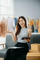 Asian lady blogger showing clothes in front of the camera to recording vlog video live streaming at her shop. photo