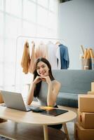 Young woman running online store Startup small business SME, using smartphone or tablet taking receive and checking online purchase shopping photo