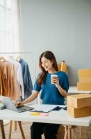 Young woman running online store Startup small business SME, using smartphone or tablet taking receive and checking online purchase shopping photo