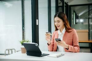 Woman using smart phone for mobile payments online shopping, omni channel, sitting on table, virtual icons graphics interface screen photo