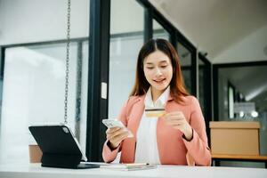 Woman using smart phone for mobile payments online shopping, omni channel, sitting on table, virtual icons graphics interface screen photo