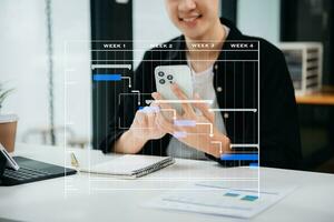 gerente de proyecto trabajando y actualizando tareas con hitos de planificación de progreso y diagrama de programación de diagramas de gantt. negocios que trabajan con teléfonos inteligentes, tabletas y computadoras portátiles foto