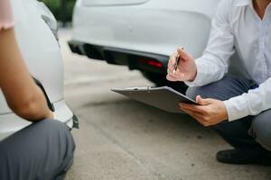 Woman and insurance agent claims process after car crash. with an Asian male Insurance Adjuster photo