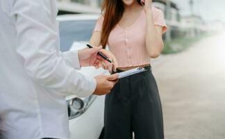 Woman and insurance agent claims process after car crash. with an Asian male Insurance Adjuster photo