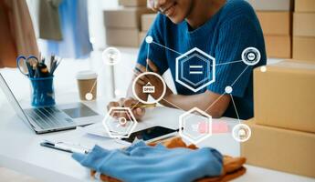 Young woman running online store Startup small business SME, using smartphone or tablet taking receive and checking online purchase shopping order photo