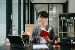 Asian Woman lawyer reading legal book with gavel on table in office. justice and law ,attorney concept. photo