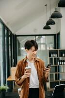 Man using smart phone for mobile payments online shopping, omni channel, sitting on table, virtual icons graphics interface screen photo