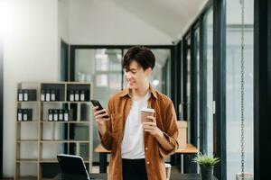 Man using smart phone for mobile payments online shopping, omni channel, sitting on table, virtual icons graphics interface screen photo