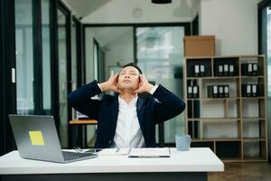 Frustrated young businessman working on a laptop computer sitting at his working place photo