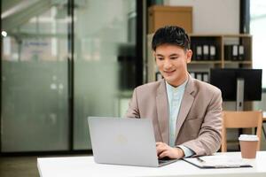 Young business man working at office with laptop, tablet and taking notes on the paper. photo