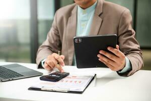 Man counting coins on calculator taking from the piggy bank. hand holding pen working on calculator to calculate on desk about cost at home office. photo