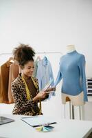 Diverse female fashion designers at work with tailor centimeters on necks and holds tablet and smartphone. independent creative design photo