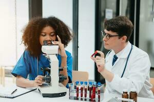 Two scientist or medical technician working, having a medical discuss meeting with an Asian senior female scientist supervisor in the laboratory with online reading, test samples photo