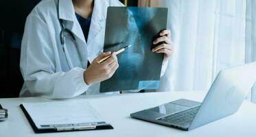 woman doctor showing x-ray lap sheet and explain the details to patient via video call system at the hospital. photo