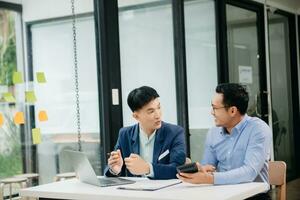 Male discussing new project with business colleague. Young man talking with young man in office. photo