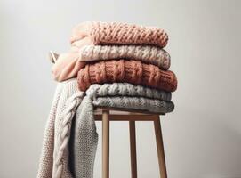 Stack of clean freshly laundered, neatly folded women's clothes on wooden table. Pile of shirts, dresses and sweaters on the table, white wall background. Created with Generative AI technology. photo