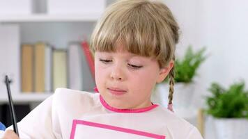 une peu fille est séance à une table avec une stylo et papier video