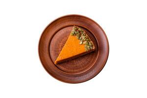 Beautiful tasty pumpkin pie with slices on a black ceramic plate photo