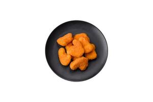 Delicious fresh crispy chicken nuggets on a dark concrete background photo