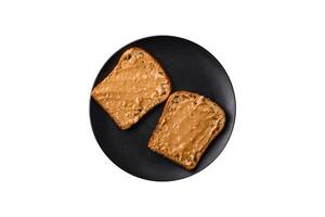 Nutritious sandwich consisting of bread and peanut butter on a black ceramic plate photo