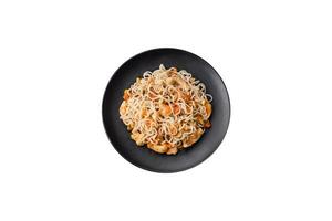 delicioso tallarines con pollo y vegetales o udon en un negro cerámico plato foto