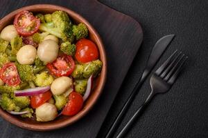 Delicious fresh salad with broccoli, cherry tomatoes, mushrooms, onions, salt, spices and herbs photo