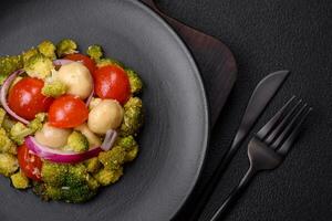 Delicious fresh salad with broccoli, cherry tomatoes, mushrooms, onions, salt, spices and herbs photo