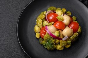 Delicious fresh salad with broccoli, cherry tomatoes, mushrooms, onions, salt, spices and herbs photo