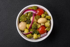 Delicious fresh salad with broccoli, cherry tomatoes, mushrooms, onions, salt, spices and herbs photo