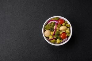 Delicious fresh salad with broccoli, cherry tomatoes, mushrooms, onions, salt, spices and herbs photo