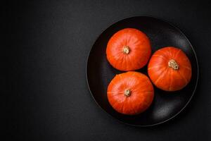 Beautiful fresh round pumpkins in orange color on a dark concrete background photo