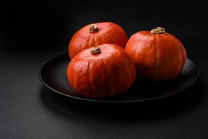 Beautiful fresh round pumpkins in orange color on a dark concrete background photo