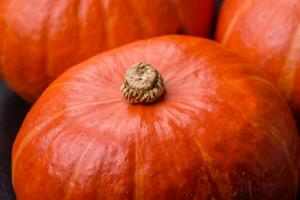 hermosa Fresco redondo calabazas en naranja color en un oscuro hormigón antecedentes foto