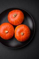 Beautiful fresh round pumpkins in orange color on a dark concrete background photo