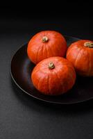 Beautiful fresh round pumpkins in orange color on a dark concrete background photo