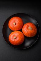 Beautiful fresh round pumpkins in orange color on a dark concrete background photo