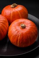 Beautiful fresh round pumpkins in orange color on a dark concrete background photo