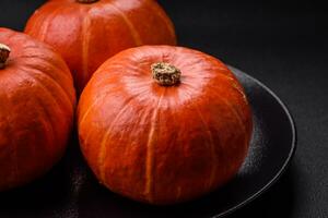 Beautiful fresh round pumpkins in orange color on a dark concrete background photo