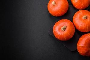 Beautiful fresh round pumpkins in orange color on a dark concrete background photo